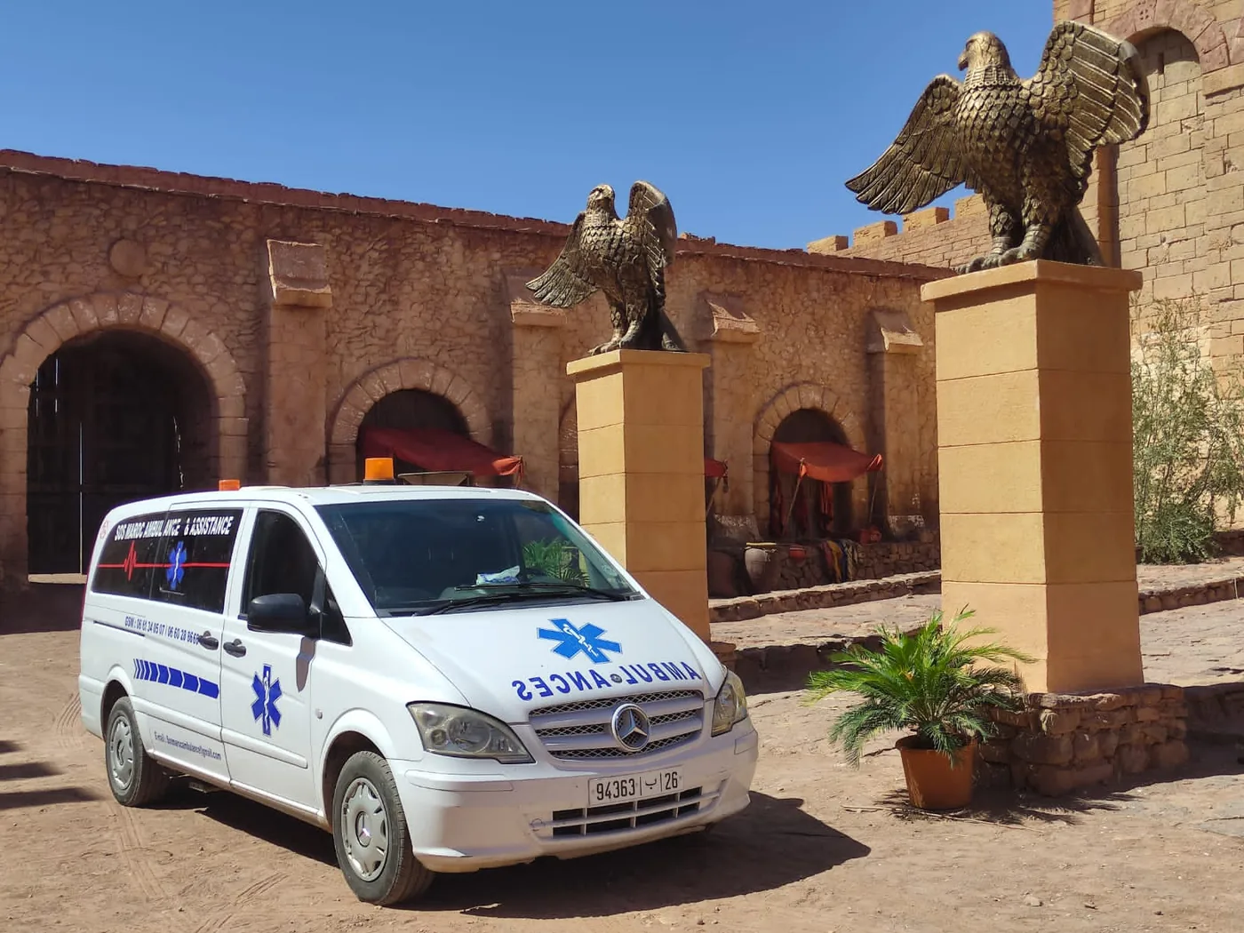 Présence médicale sur site sécurisé — Ambulance et agent terrain devant un poste médical ou site sécurisé pour assistance, prévention et coordination opérationnelle.